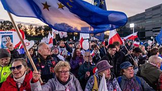 People wave Polish and EU flags as they gather outside a tv studio where main candidates in the upcoming Polish elections are taking part in a debate in Warsaw, Poland.