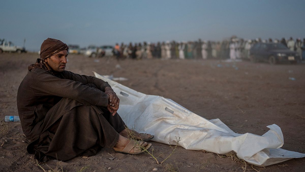 Afegão sentado ao lado de familiar morto, vítima do sismo de sábado
