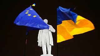 DATEI - Foto vom 5\. Dezember 2013: Oppositionelle Demonstranten halten die Flaggen der EU und der Ukraine (rechts) um ein Denkmal des ukrainischen Dichters Taras Schewtschenko in der Innenstadt von Donezk.