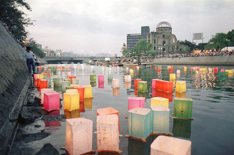 The Atomic Bomb Dome is seen over colourful paper lanterns floating down Hiroshima’s Motoyasu river, August 1988
