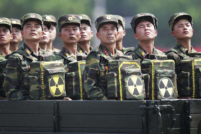North Korean soldiers turn and look towards leader Kim Jong Un as they carry packs marked with the nuclear symbol in Pyongyang, July 2013