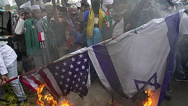 Manifestantes muçulmanos queimam bandeiras dos EUA e de Israel, à porta da embaixada norte-americana em Jacarta, Indonésia