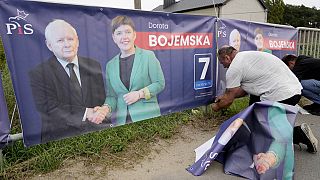 A man puts up election banners for a PiS party candidate, including an image of the party leader Jaroslaw Kaczynski, in Czosnow near Warsaw, on Wednesday, Oct. 11, 2023. 