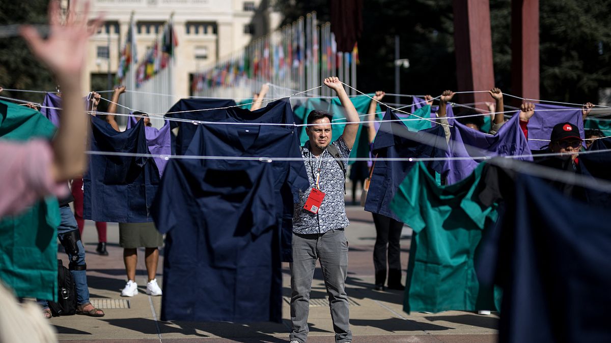 Nurses hold scrubs during a demonstration against staff shortages in front of the UN, October 12, 2023