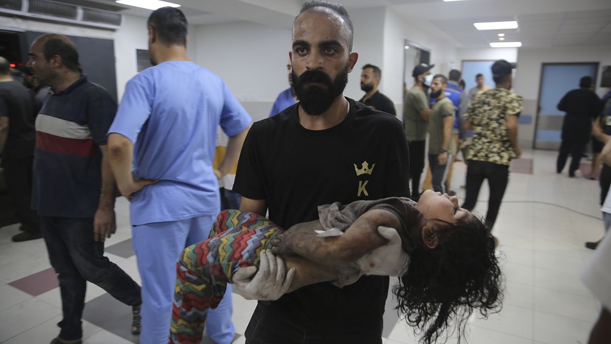 Ein Mann in einem Krankenhaus in Gaza hält ein verletztes Mädchen im Arm