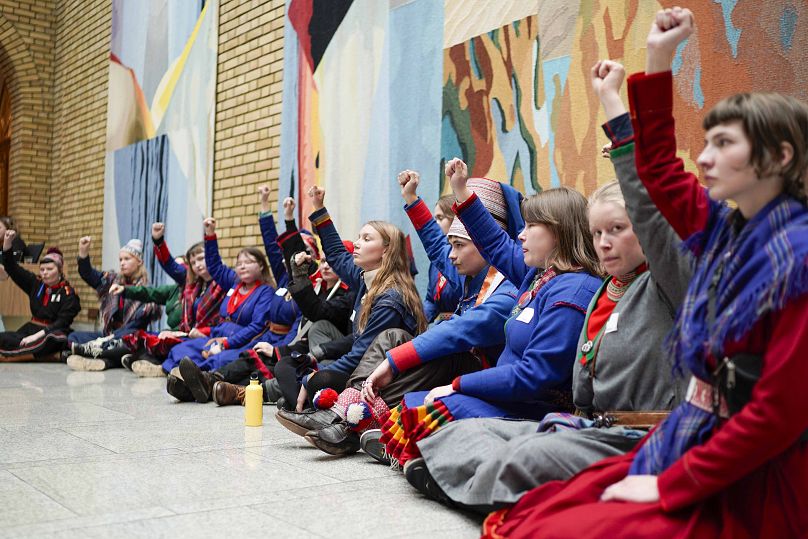 Activists wearing traditional Sami costumes demonstrate inside the central hall of Storting, the Norwegian parliament, in Oslo, 11 October 2023.