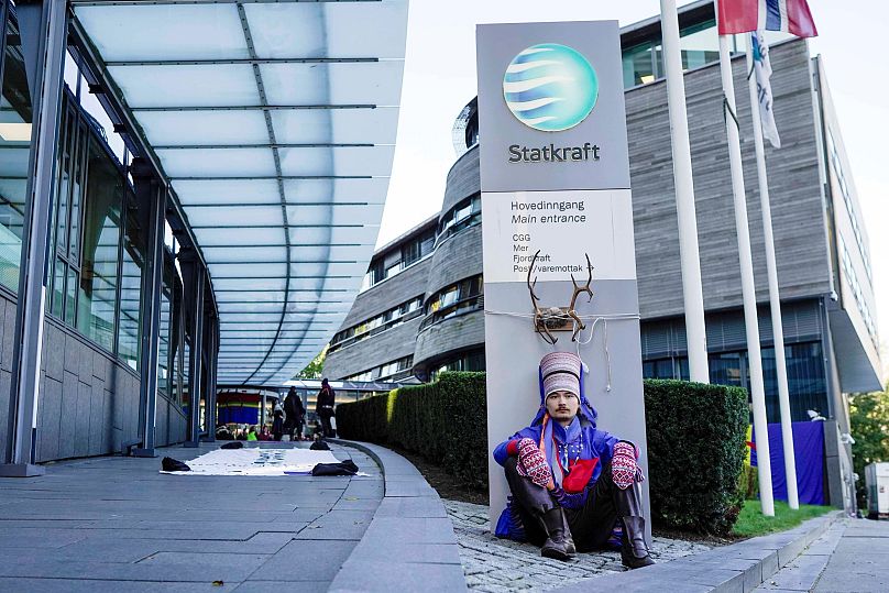 Activist Mihkkal Hætta wears a traditional Sami outfit as he sits in protest outside the entrance of Statkraft, a state-owned company that operates 80 of the wind turbines.