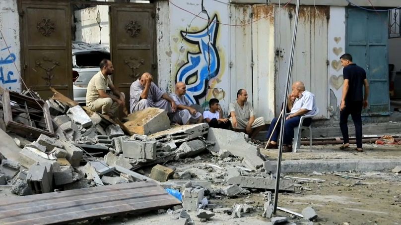 مجموعة من سكان غزة قرب الدمار الناجم عن القصف الإسرائيلي