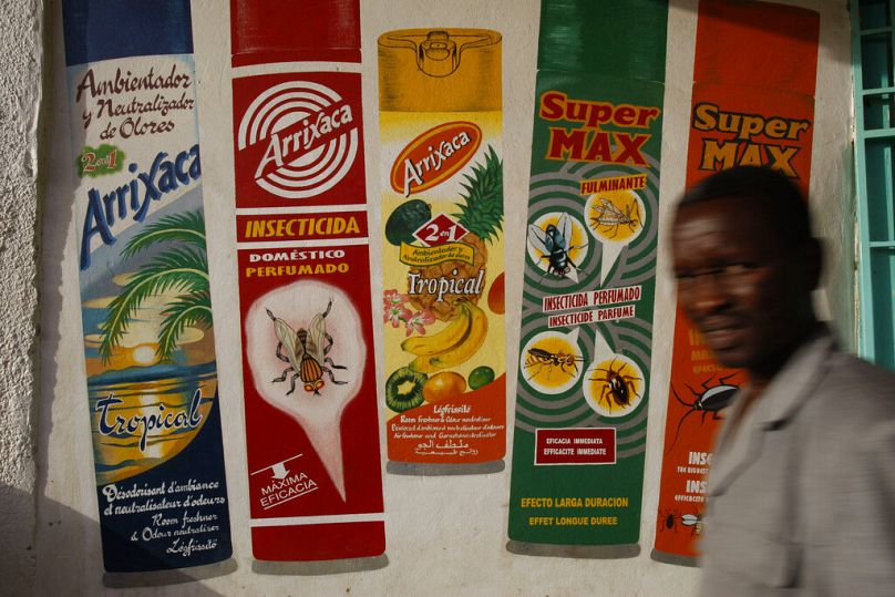 A man walks past advertisements for household insecticides painted on a grocery store in the "Petit Marche" market area of Niamey, February 2010