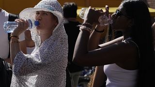  Туристи пият студена вода, до момента в който се крият от парещ безоблачен следобяд покрай Колизеума в Рим, 5 юли 2023 година 