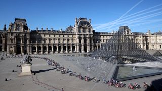 A mezőny a párizsi Louvre múzeum piramisa mellett a 109. Tour de France francia országúti kerékpáros körversenyen 2022. július 24-én – képünk illusztráció.