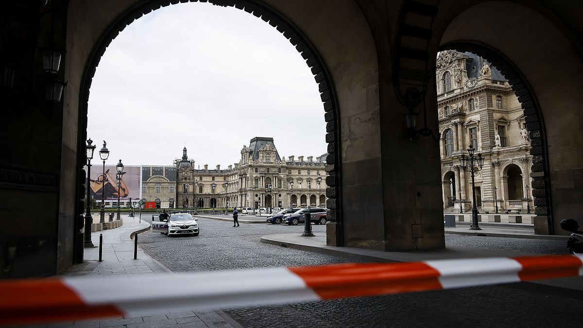 Police officers stand guard outside the Louvre Museum as people are evacuated after it received a written threat