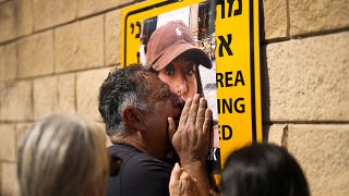 Eli Albag cries over the photograph of his daughter Liri, as he gathers with others during a protest 