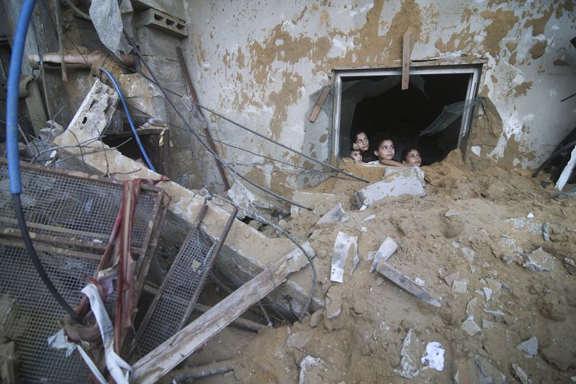 Des enfants palestiniens regardent par la fenêtre de leur habitation, détruite par des frappes aériennes israéliennes à Rafah, dans la bande de Gaza, samedi 14 octobre 2023