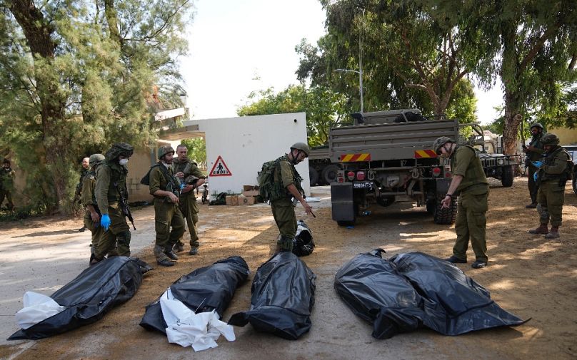 A Kfar Aza kibuc vétlen áldozatait gyűjtik össze az izraeli katonák 2023. október 10-én