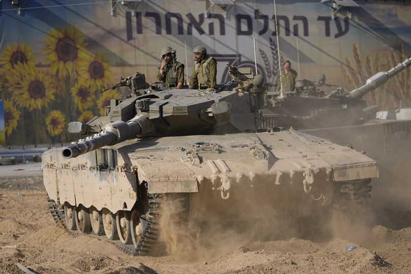 Des soldats israéliens déplacent un char dans une zone de transit près de la frontière avec la bande de Gaza, dans le sud d'Israël, dimanche 15 octobre 2023