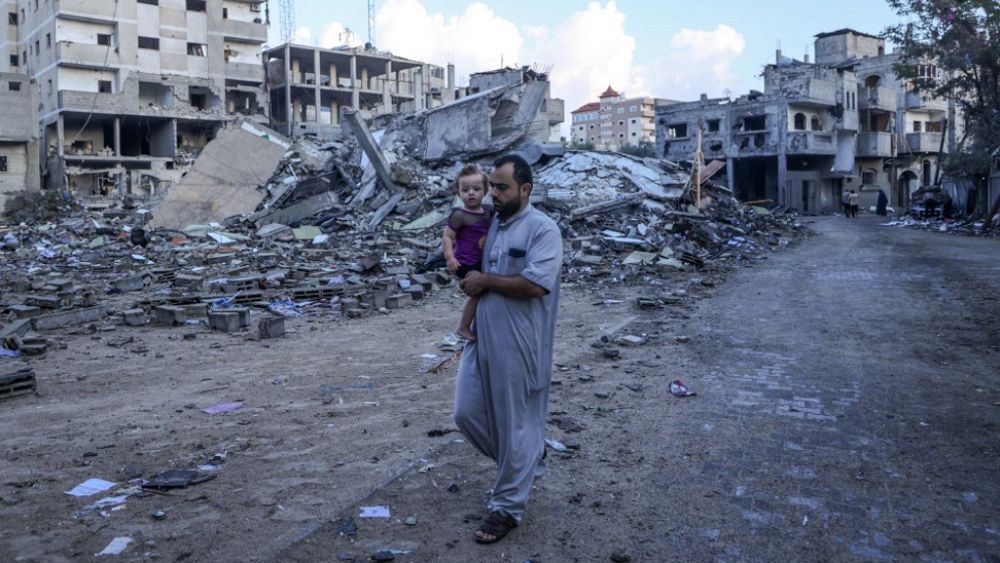 Палестинец върви сред развалините на сгради разрушени по време на