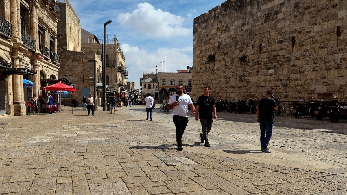 People walk into Jerusalem's Old City via Jaffa Gate, as the conflict wreaks havoc across the tourism sector 11 October, 2023. 