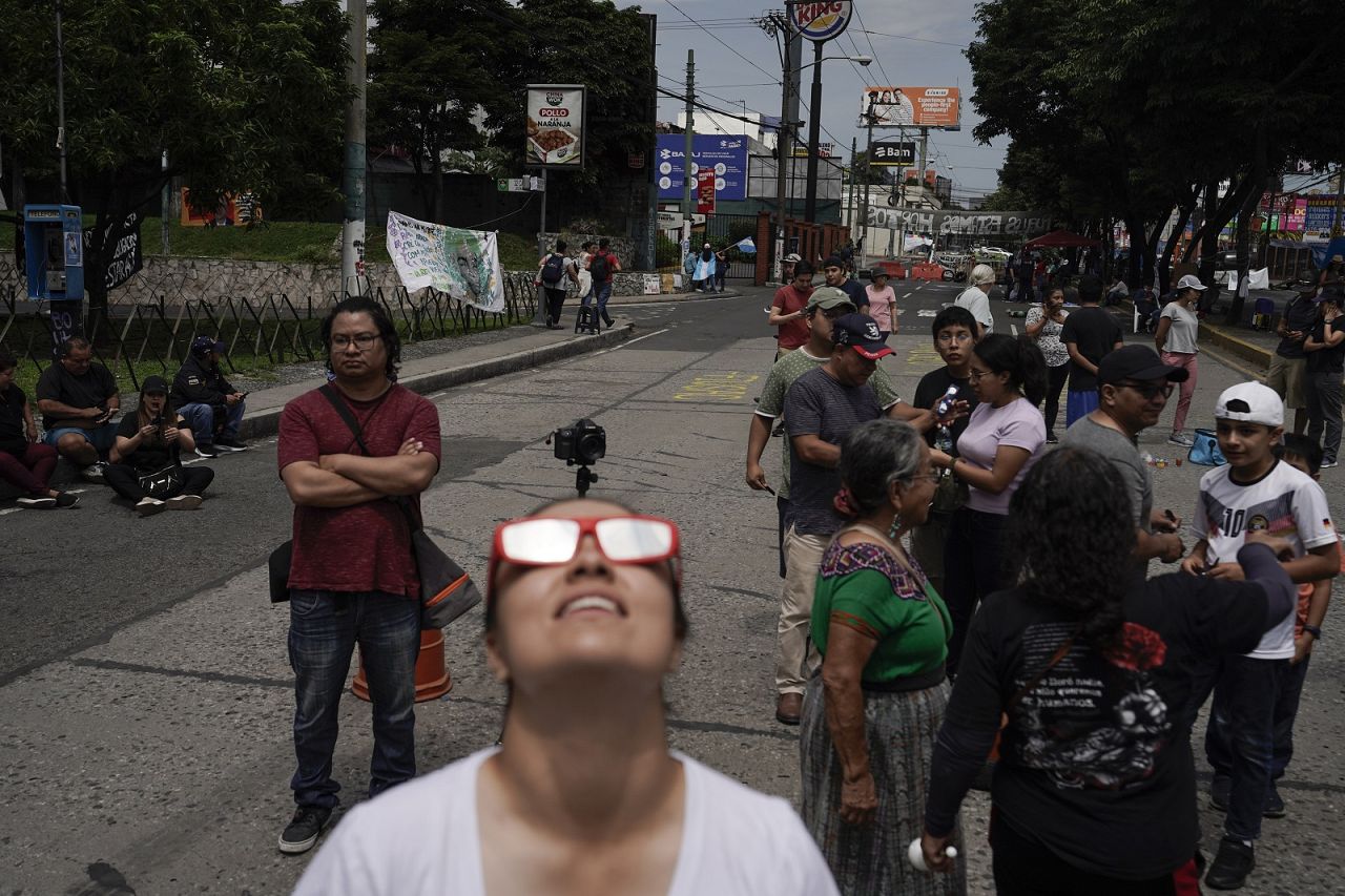 People watch the "ring of fire" solar eclipse at a blocked street by protestors in Guatemala City.