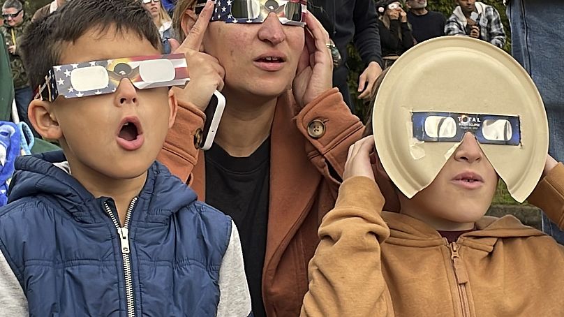 Samia Harboe, her son Logan and her friend&apos;s son wear eclipse glasses during totality of the annular solar eclipse in Eugene, Oregon, US on Saturday, October 14, 2023.