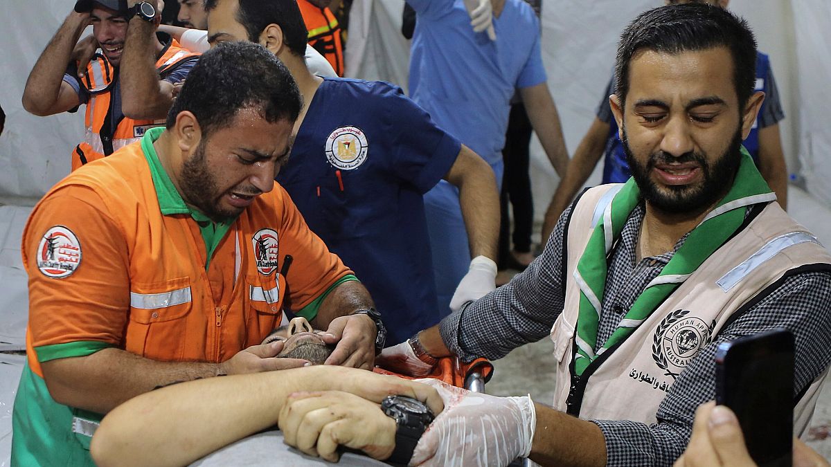عناصر من الدفاع المدني والطوارئ يبكون فوق جثمان أحد زملائهم الذين قتلوا ليلة الإثنين إثر قصف إسرائيلي على مدينة غزة