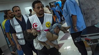 مسعفون يحملون طفلا فلسطينيا مصابا لعلاجه في مستشفى الشفاء في غزة