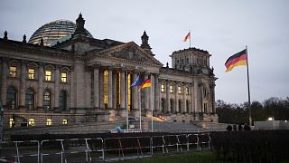 Banderas nacionales alemanas ondean frente al edificio del Reichstag con el Parlamento alemán Bundestag en Berlín, Alemania.