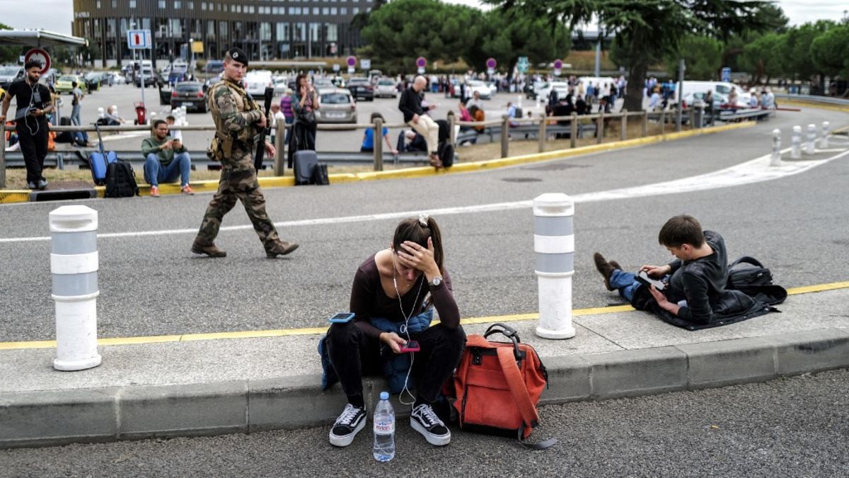 Passengers wait as a French soldier patrols outside the Toulouse-Blagnac Airport in Blagnac, southwestern France, on 18 October 2023. 