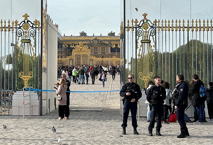 French police stand guard in front of the Palace of Versailles as tourists enter again after the Palace was evacuated for security reasons on 17 October.