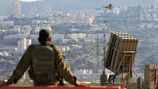 یک سرباز اسرائیلی در کنار سامانه پدافند موشکی گنبد آهنین