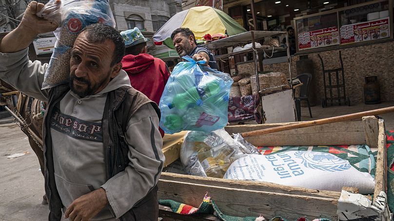 Palestinianos recolhem alimentos fornecidos pela Agência das Nações Unidas para Refugiados Palestinianos (UNRWA) na Cidade de Gaza, maio de 2021