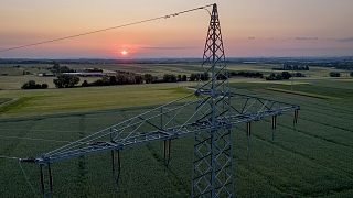 A transmission tower stands on a field in the outskirts of Frankfurt, Germany, as the sunrises on June 6, 2023. 