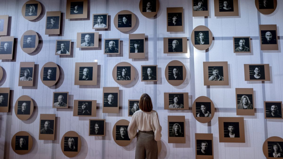 A woman stands in front of a wall with pictures of Slovenian authors in the Slovenian pavilion at the Book Fair in Frankfurt, Germany, Tuesday, Oct. 17, 2023.