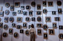 A woman stands in front of a wall with pictures of Slovenian authors in the Slovenian pavilion at the Book Fair in Frankfurt, Germany, Tuesday, Oct. 17, 2023.
