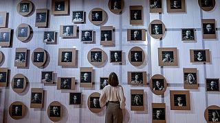  Жена стои пред стена със фотоси на словенски създатели в словенския павилион на Панаира на книгата във Франкфурт, Германия, вторник, 17 октомври 2023 година 