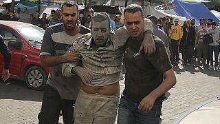 Dos personas trasladan a uno de los heridos en el hospital de Gaza