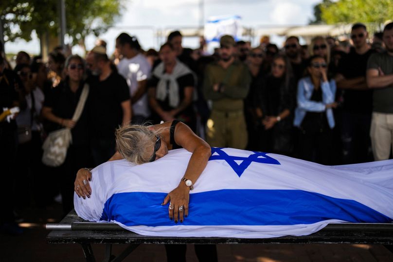 A mother cries over her son's body covered with the Israeli flag at Pardes Haim cemetery in Kfar Saba, near Tel Aviv, October 2023