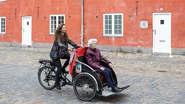 "Un Vélo Pour Tous" derneğinin bir gönüllüsü ve üyesi, 5 Mayıs 2019 tarihinde Kopenhag'ın merkezinde yaşlı bir kadını kargo bisikletiyle taşıyor.