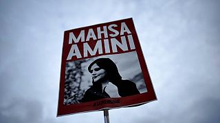 İran'da kıyafet kurallarına uymadığı iddiasıyla polis gözetemindeyken hayatını kaybeden Mahsa Amini'nin fotoğrafının bulunduğu döviz