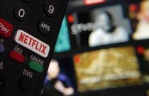Le bouton Netflix d'une télécommande de télévision est juxtaposé à une page web de Netflix, en février 2023.