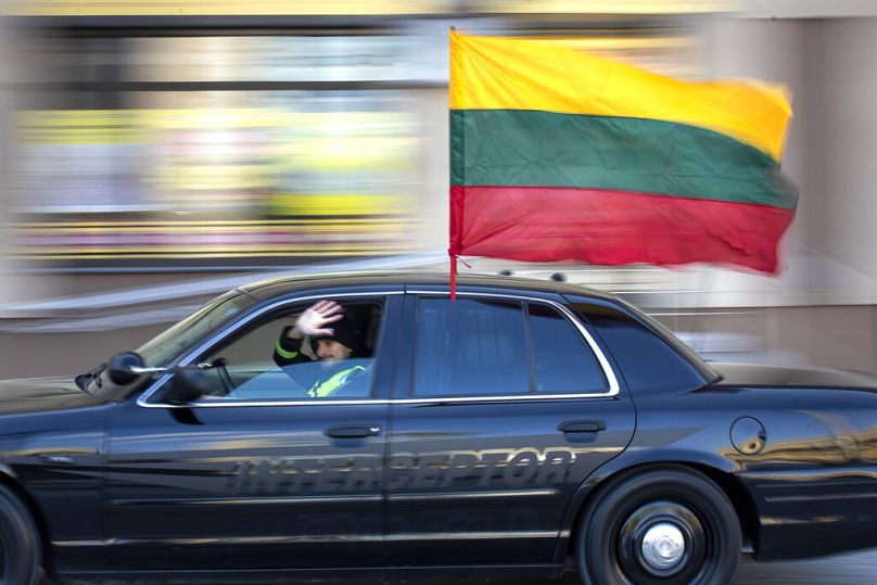 A car with a Lithuanian national flag drives along Gediminas Avenue during a celebration of Independence day in Vilnius, Lithuania, Thursday, March 11, 2021.