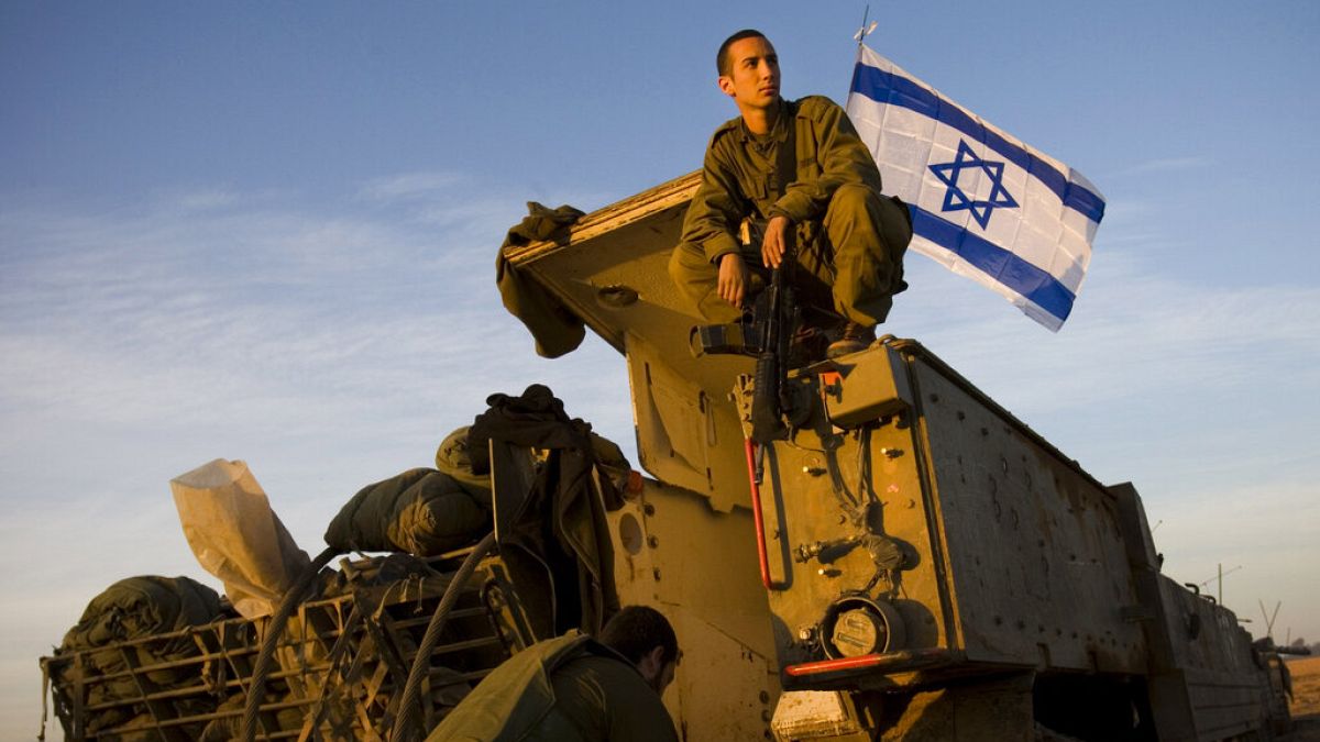 An Israeli soldier sits atop of an armored vehicle at a staging area near Israel's border with Gaza, in southern Israel, 
