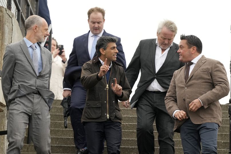 British Prime Minister Rishi Sunak , centre, gestures as he walks to meet members of the Essex Pedal club during his visit to Clacton-on-Sea, October 2023