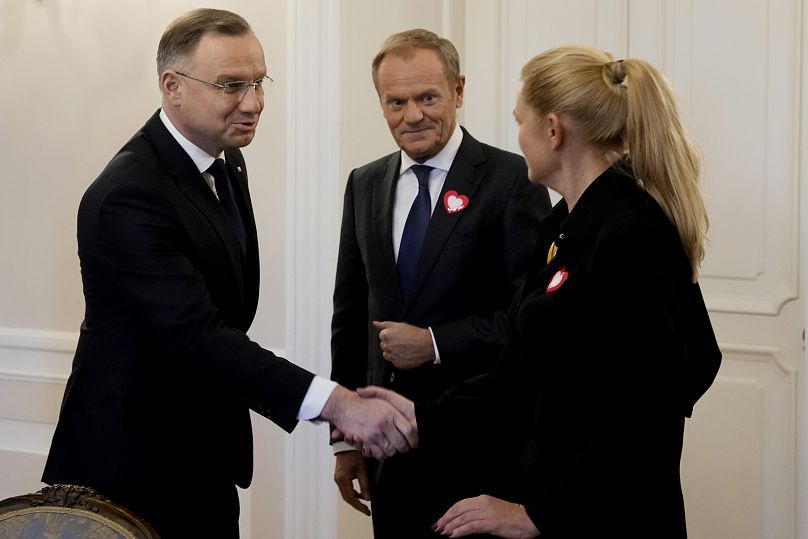 President Andrzej Duda, left, shakes hands with opposition party member Barbara Nowacka, right, as the top opposition leader Donald Tusk looks on, in Warsaw, on Tuesday.