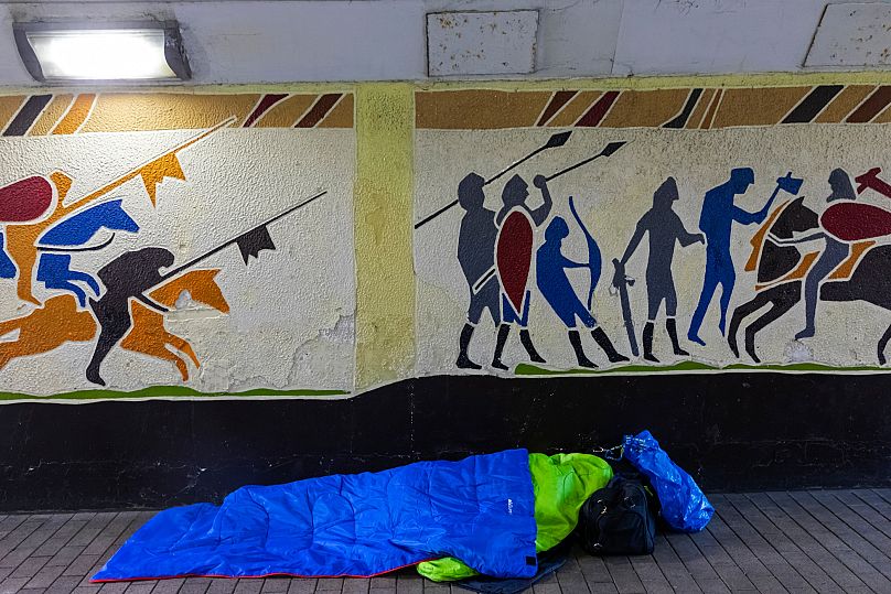 A rough sleeper in Hastings, in front of a mural depicting the 1066 Norman invasion of England