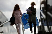 ARCHIVO - Dos mujeres caminan cerca de banderas de la UE frente a la sede de la Comisión Europea en Bruselas, el lunes 27 de mayo de 2019.