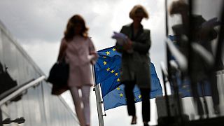 FILE - Two women walk near EU flags outside the European Commission headquarters in Brussels, Monday, May 27, 2019.