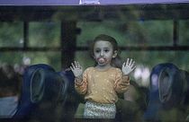 Uma criança olha pela janela de um autocarro enquanto a sua família parte da cidade de Kiryat Shmona, no norte de Israel