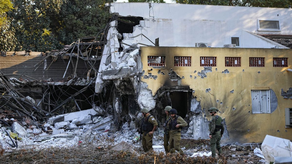 Des soldats israéliens passent devant des maisons détruites par des militants du Hamas dans le kibboutz Beeri, en Israël, le samedi 14 octobre 2023.