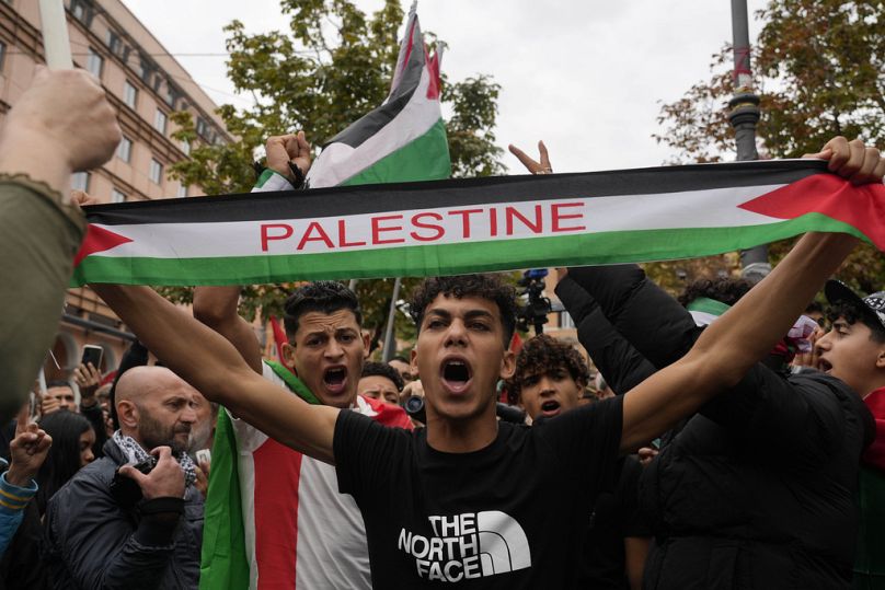 Protesters hold flags and shout slogans gather for a pro-Palestinian rally in Rome, Saturday, Oct. 21, 2023